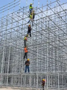 Ringlock scaffolding erection inspection at construction site with workers checking scaffold alignment and components