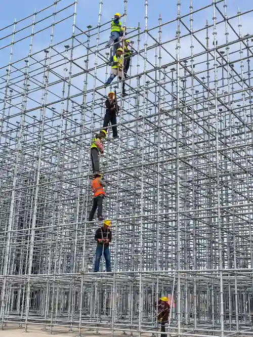 Ringlock scaffolding erection inspection at construction site with workers checking scaffold alignment and components
